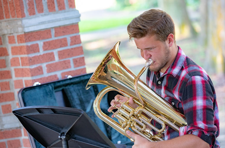 A University of Louisiana at 69传媒 student plays his euphonium outdoors on campus
