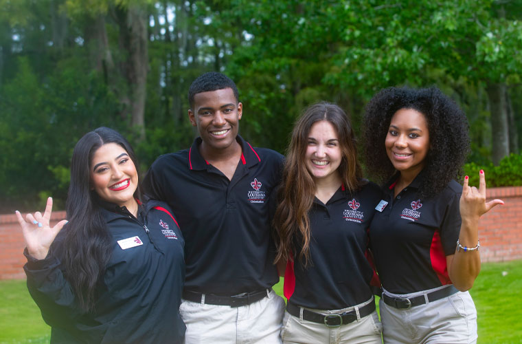 A group of University of Louisiana at 69传媒 orientation leader students smiling at the camera and holding up the UL hand sign