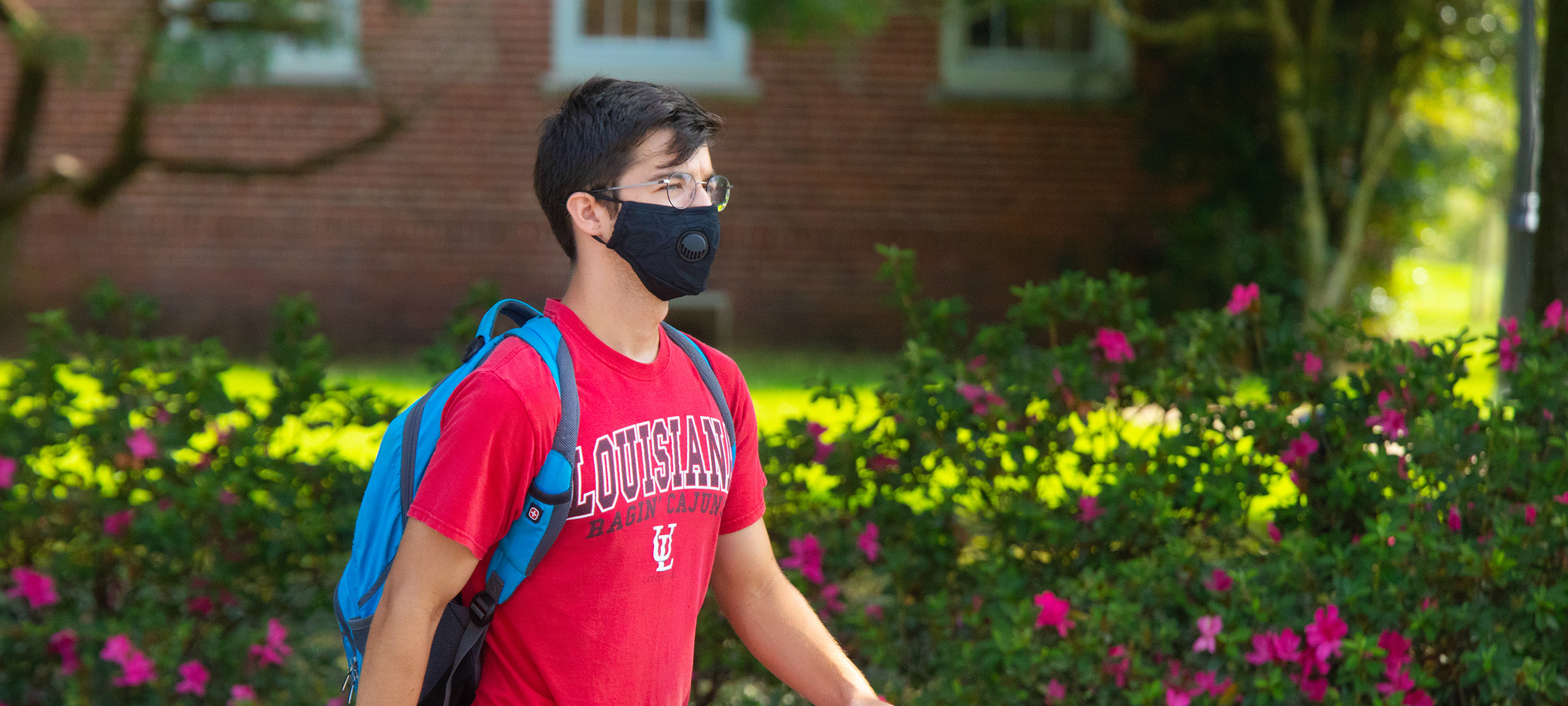 Student walking on UL 69传媒's campus with a mask