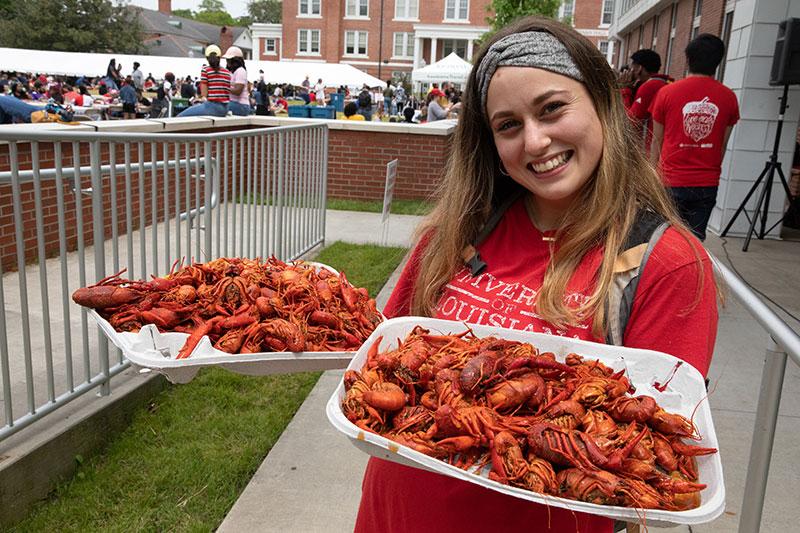 University of Louisiana at 69传媒 student holding two trays of boiled crawfish during the annual tradition Lagniappe 69传媒