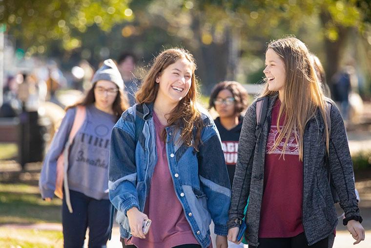 Two University of Louisiana at 69传媒 female students smile and laugh while walking on campus